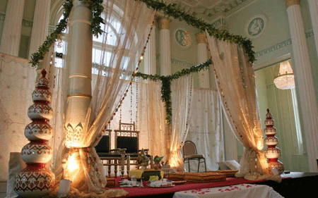 Wedding stage cum mandap decorated with white drapes and green leaves